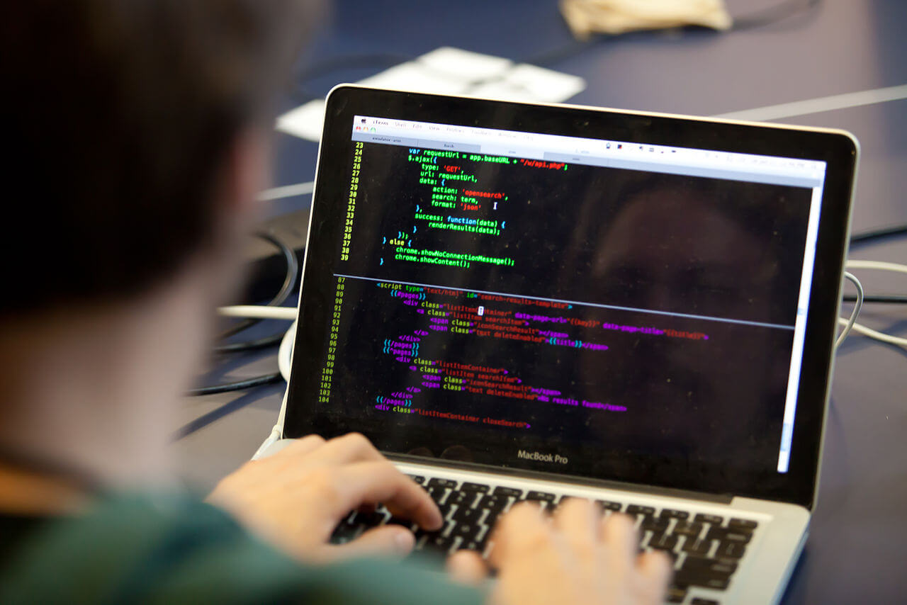 A programmer writing code on a laptop