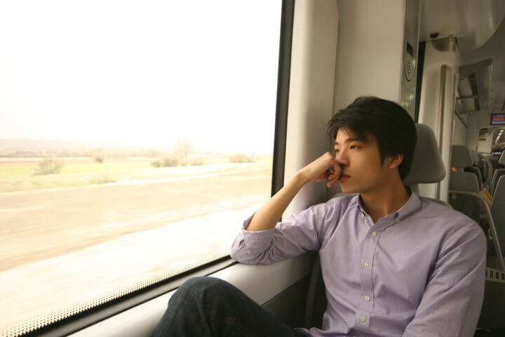 A man is deep in thought while riding on a train.