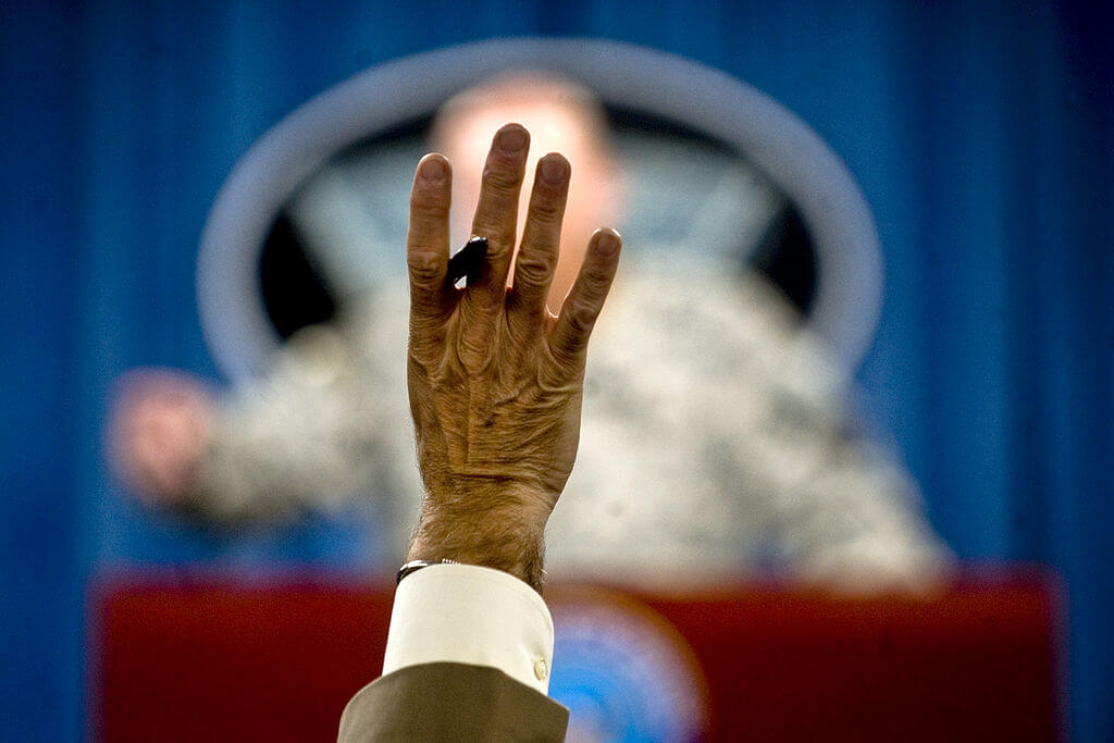 A reporter raises his hand to ask a question at a press conference