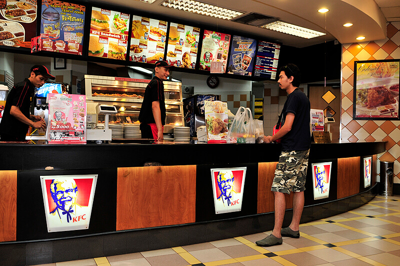 Several cashiers take orders for a KFC restaurant in Indonesia.