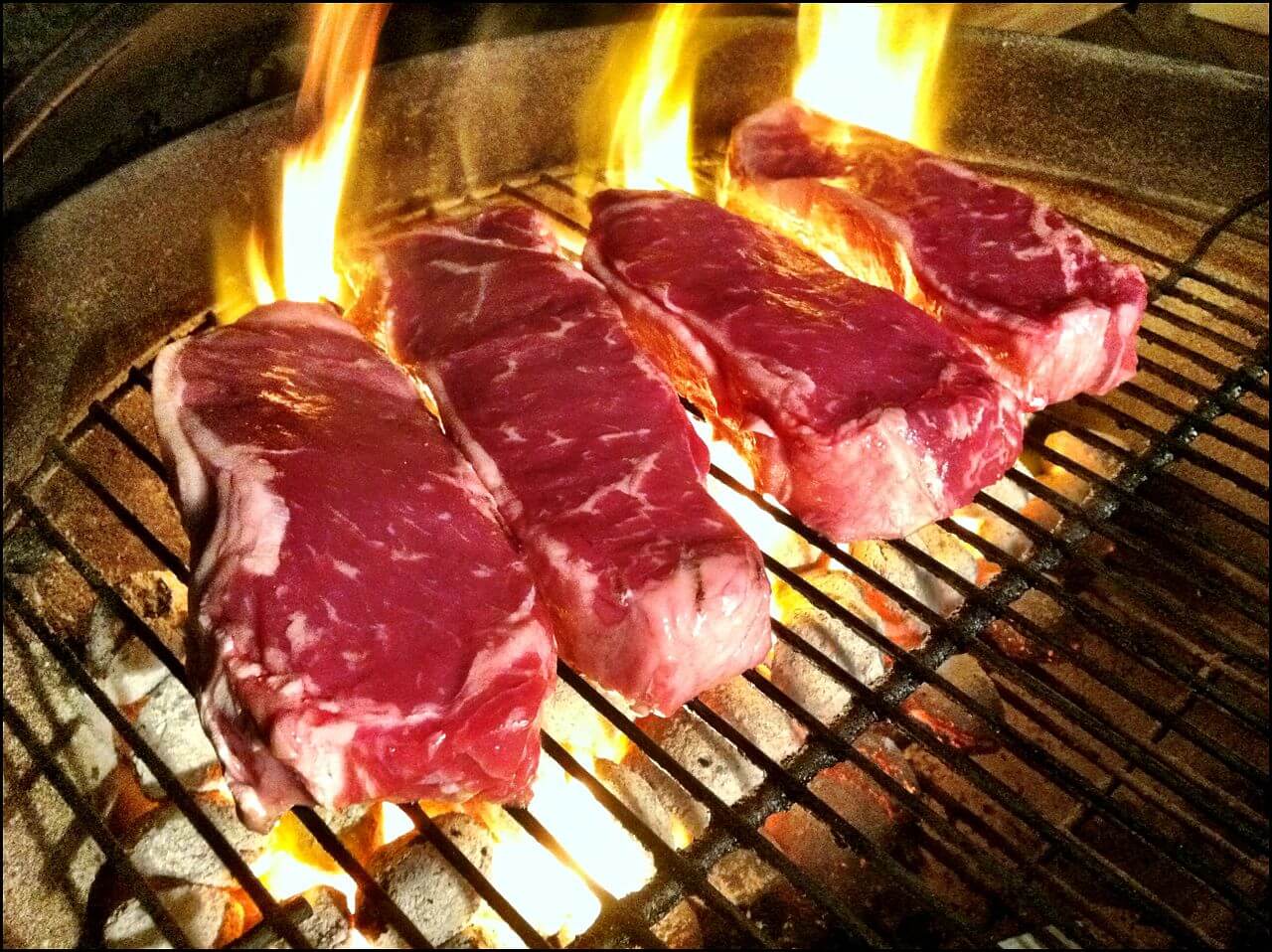 A set of four steaks on a grill