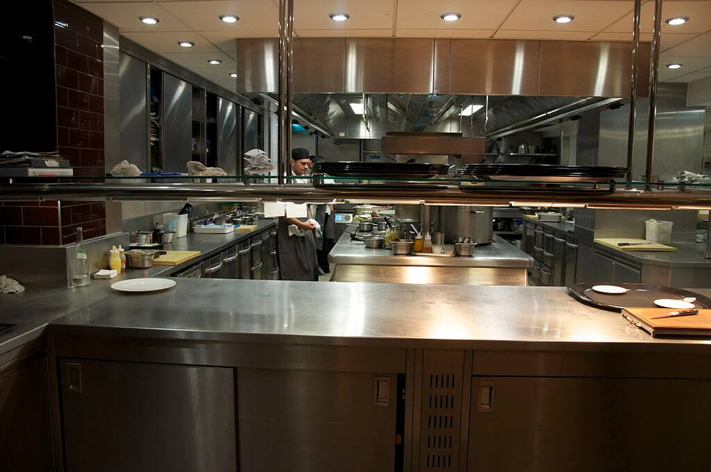 A professional kitchen, showing equipment such as ovens, knives, cutting boards, and ranges.