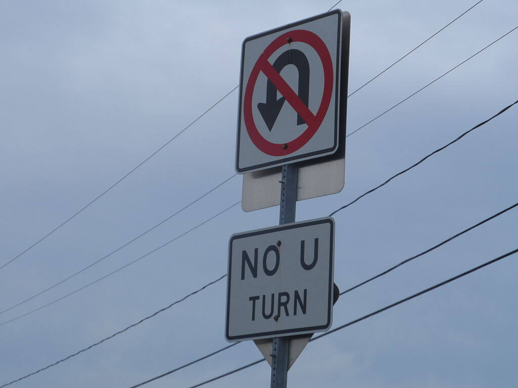 A "No U-Turn" sign on a cloudy day