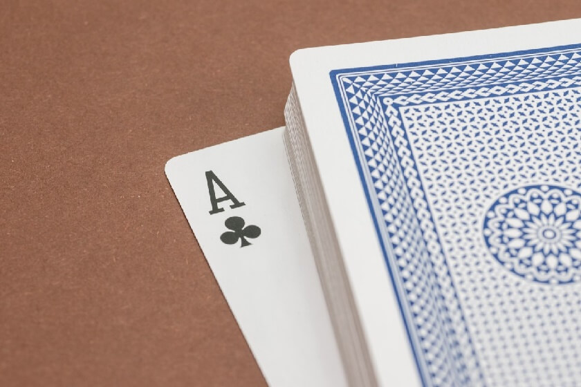 A shuffled deck of cards, with the Ace of Spades peeking out from the bottom