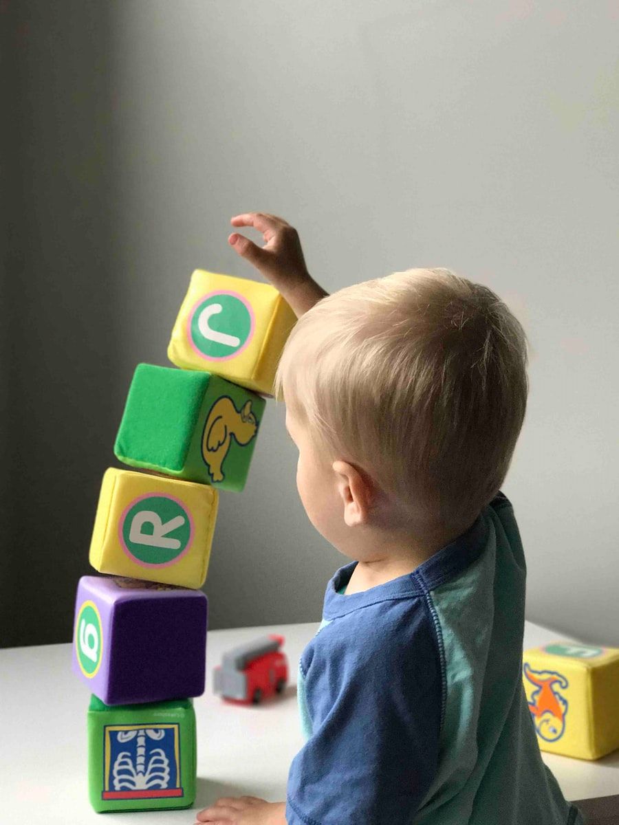 A young boy stacks blocks, and they start to topple over.