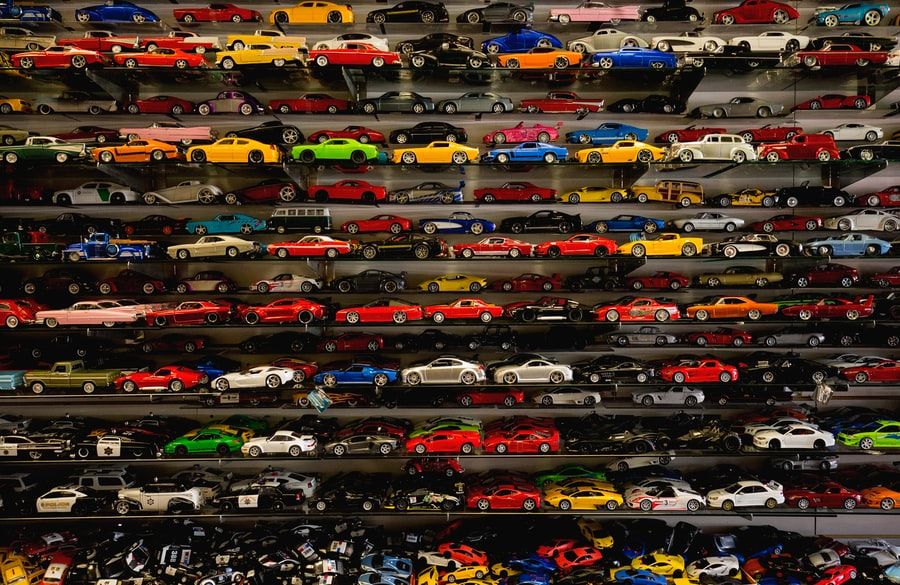 A large, varied collection of toy and model cars sits on several small shelves.