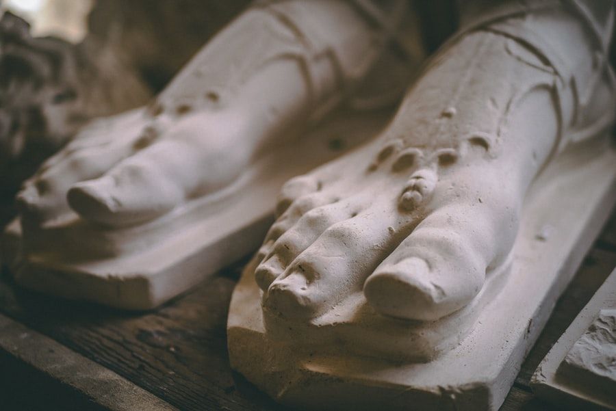 A closeup of a marble statue's feet, showing the detail on the toes and the foot jewelry.