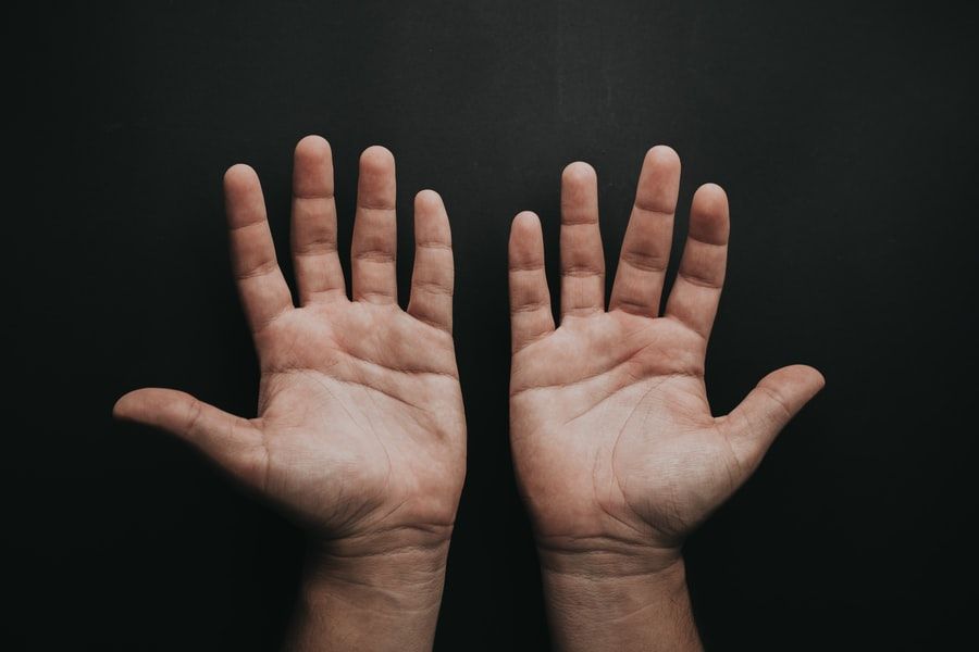 A closeup of two hands against a black background.